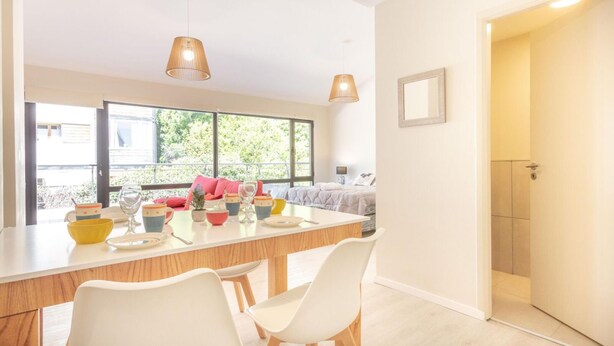 A modern kitchen with a large island, white chairs, and pendant lights. - Departamento en Bariloche con Terraza (San Carlos de Bariloche)
