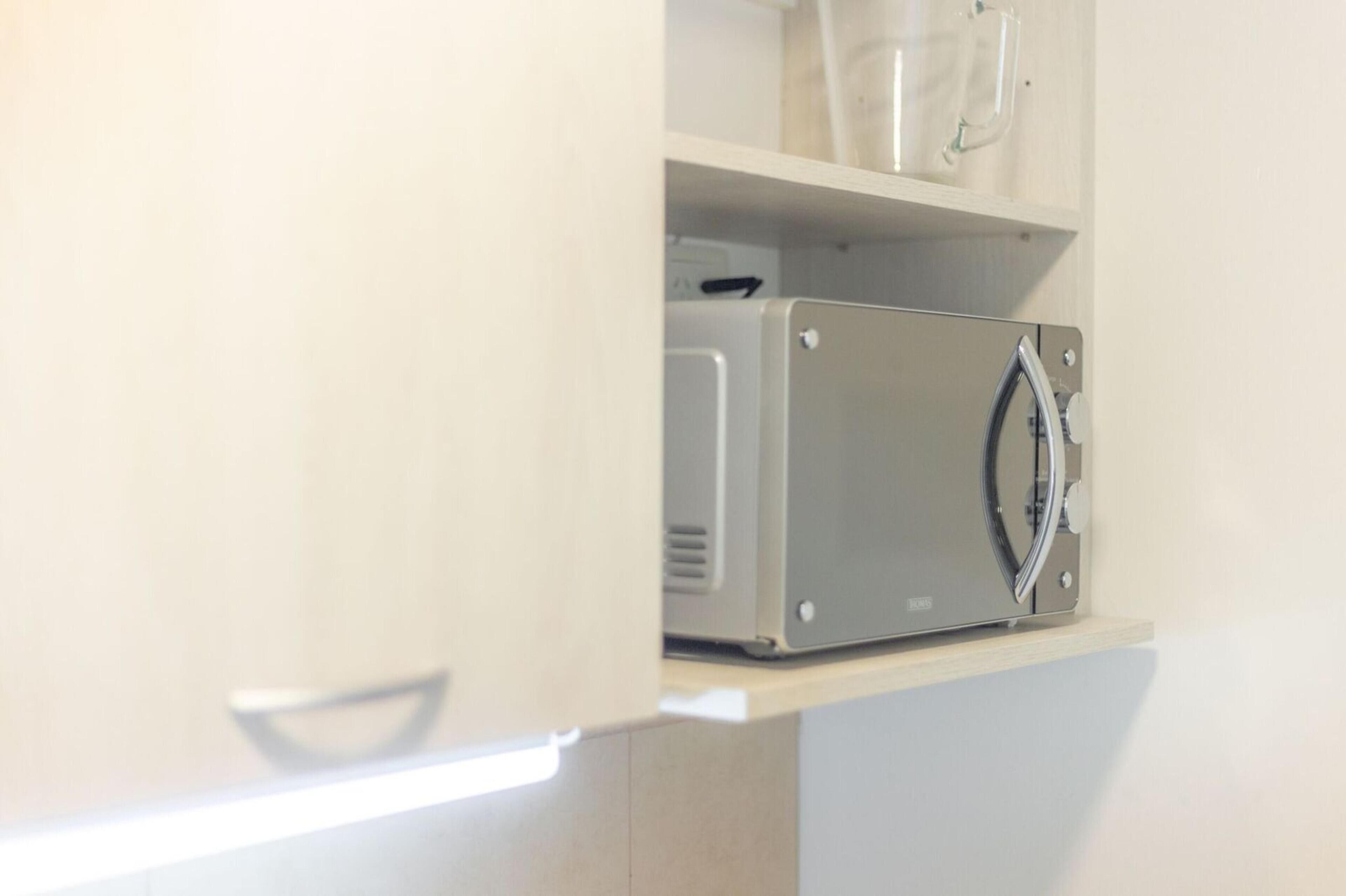 A kitchen with a microwave on a shelf.
