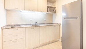 A modern kitchen with light wood cabinets, a stainless steel refrigerator, and a microwave. - Departamento en Bariloche con Terraza (San Carlos de Bariloche)