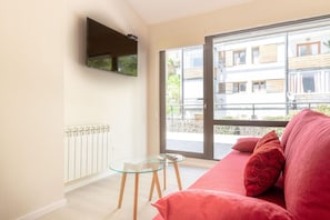 Relax in this stylish living room with a large window offering a view of the city, a comfortable sofa, and a flat-screen TV.
