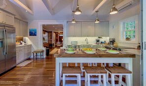 Una cocina moderna con una isla central, taburetes de madera e iluminación colgante.