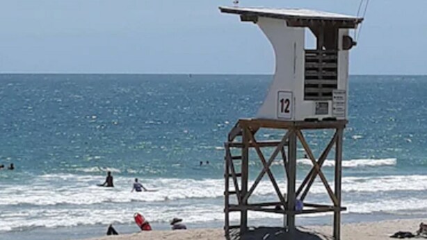 A lifeguard tower with the number 12 on a beach with the ocean in the background. - Surf Suites (Wrightsville Beach)
