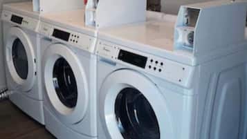 A row of white front-loading washers and dryers in a laundry room.