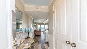 A hallway with a kitchen area, a dining table, and a sofa.