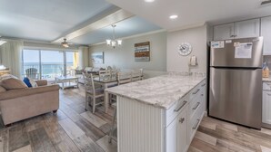 A modern kitchen with a stainless steel refrigerator, white cabinetry, and a marble countertop.