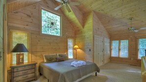Une chambre confortable, aménagée dans un chalet en bois, avec un lit, des lampes de chevet et un ventilateur de plafond.