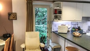 Un espacio habitable compacto con comedor, cocina equipada con refrigerador y un taburete pequeño.