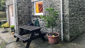 Un edificio de piedra con una mesa de picnic de madera y una planta en maceta.