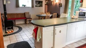 Una cocina compacta con una isla central, armarios blancos y un comedor con sillas y un banco.