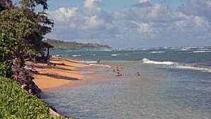 Una playa con aguas cristalinas, una orilla arenosa y algo de vegetación.