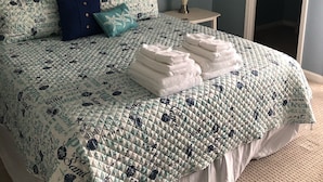 A bedroom with a bed, a ceiling fan, a nightstand with a lamp, and a door. - Relaxing Lake and Fairway view condo.        5 Star reviews. Clean and quiet. (Pawleys Island)