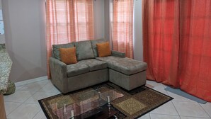 A living room with a sectional sofa, a glass coffee table, and a patterned rug. - Malay Getaway and taxi service (Laborie)