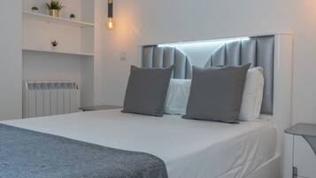 A modern bedroom with a bed, bedside tables, a radiator, shelves with plants, and a hanging light fixture.