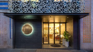 L'ingresso di un edificio moderno con un logo circolare, porte in vetro e piante in vaso.