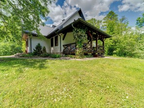 A house with a porch, surrounded by a grassy lawn and trees.