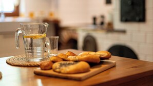 Una encimera de cocina con una jarra de vidrio, un vaso y una tabla de madera con pasteles.