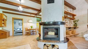 Una sala de estar acogedora con chimenea, vigas de madera, comedor y cocina.