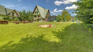 Et boligområde med et stort hus, gyngestativ og et picnicbord.