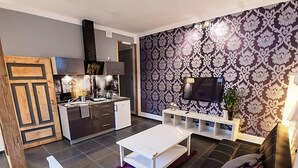 A modern living room with a black sofa, a white coffee table, and a TV mounted on a patterned wall. - Apartment Fiolet by Interhome (Szczawno Zdroj)
