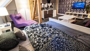 A modern living room with a sofa, a coffee table, and a TV. There is a kitchen area with cabinets and a stove. - Apartment Fiolet by Interhome (Szczawno Zdroj)