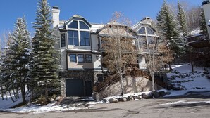 A large, two-story house with a stone facade, multiple windows, and a prominent front entrance. - Meadows Townhome (Avon)