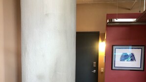 Ein Flur mit Holzboden, einer weißen Säule, einer blauen Tür und einer roten Wand mit einem gerahmten Bild.