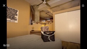 Ein Schlafzimmer mit einem Bett, einer Kommode, einer Hängelampe und einer Wandkarte.