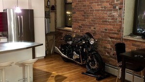 Eine Küche mit einem Edelstahlkühlschrank, einem Motorrad und einer Ziegelwand.