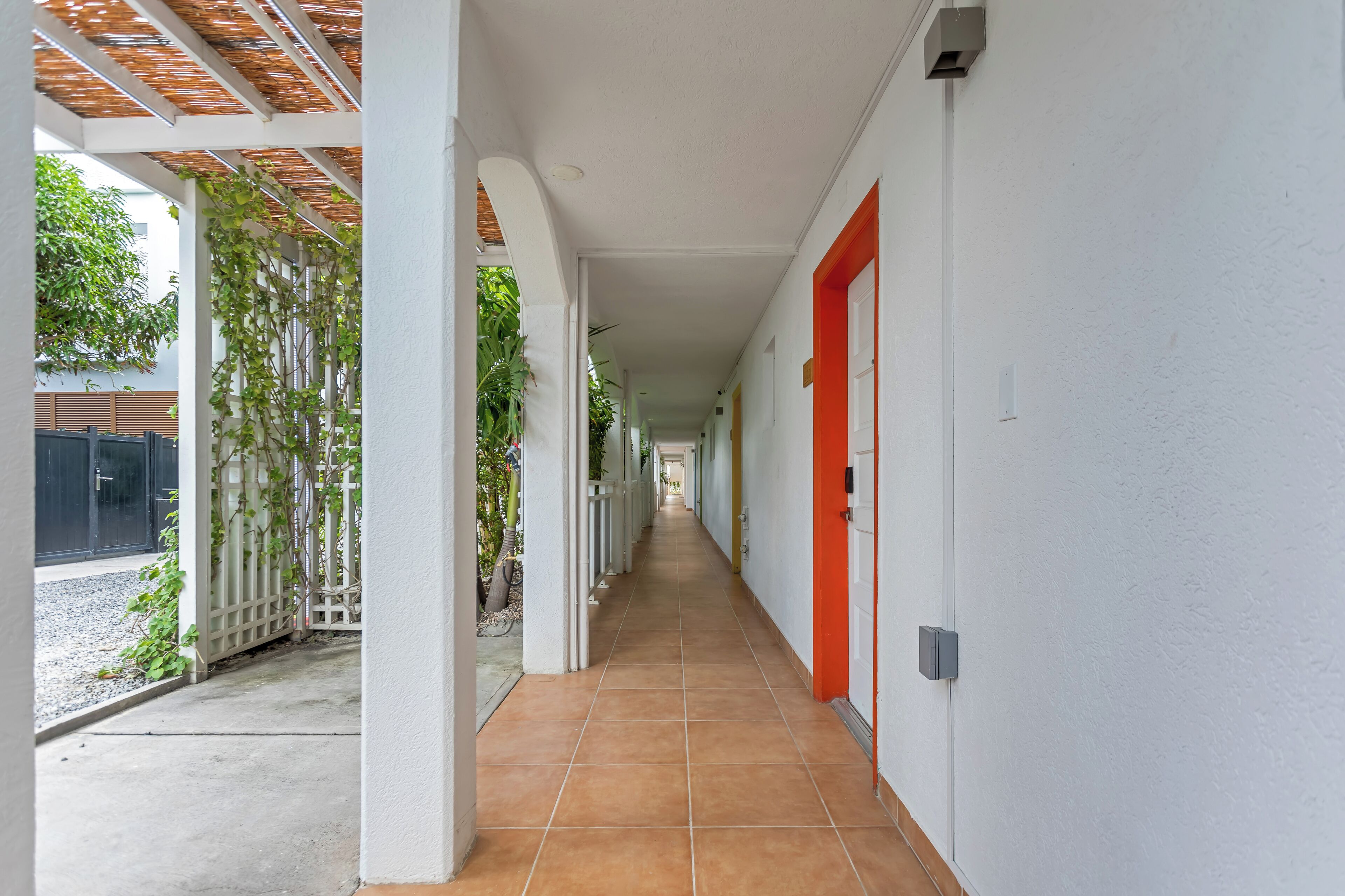 A corridor with white walls, a red door, and a tiled floor.