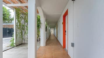 A corridor with white walls, a red door, and a tiled floor.