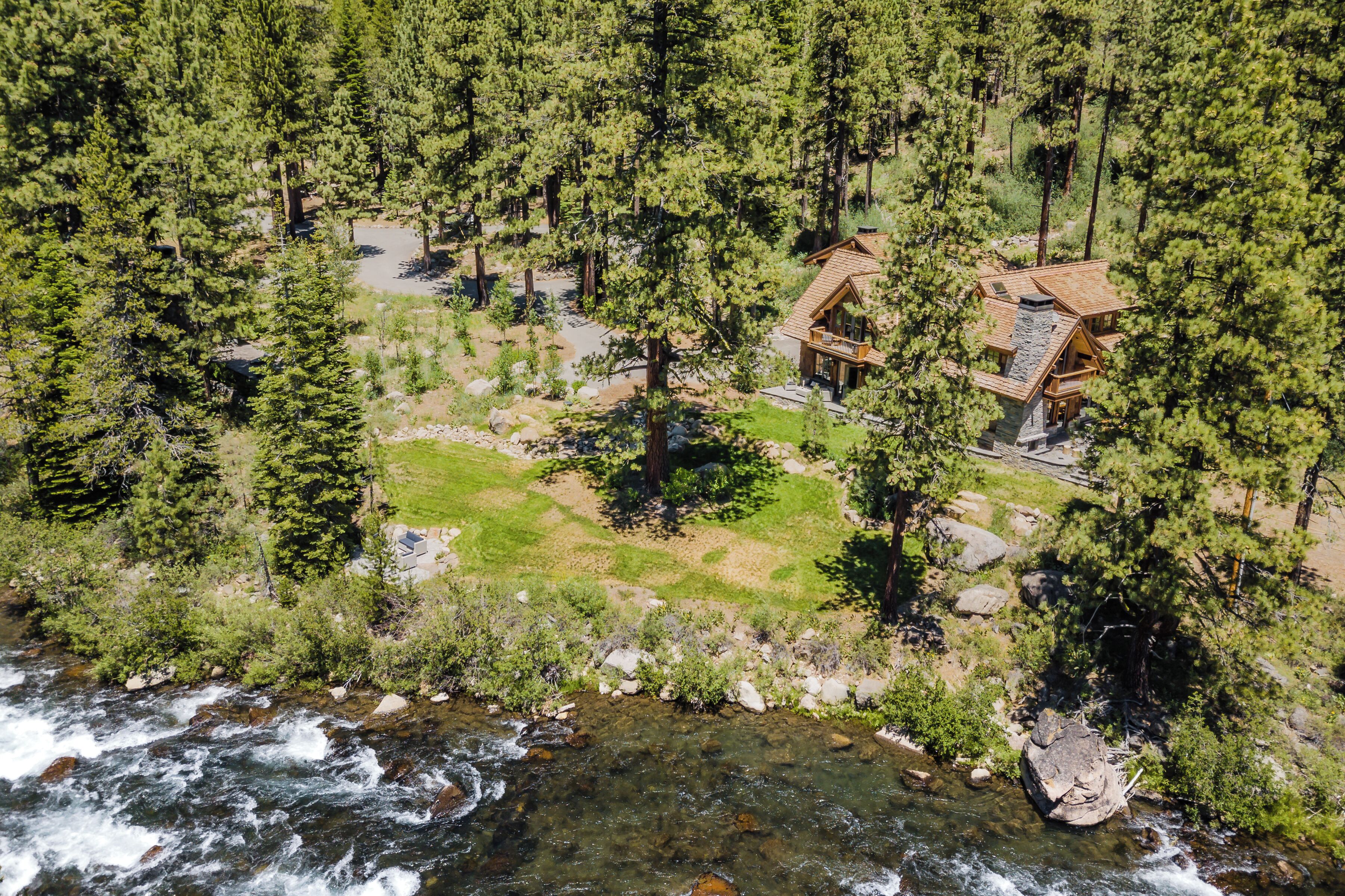 Un chalet entouré d’une forêt dense, bordé d’un ruisseau aux eaux claires et doté d’une pelouse bien entretenue.
