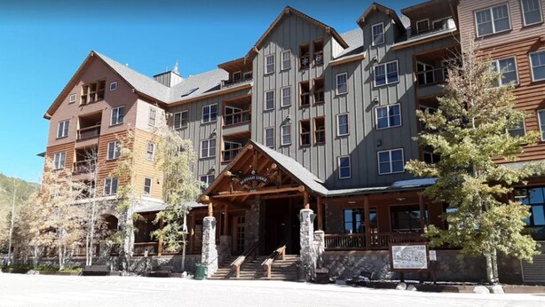 A multi-story hotel with a central entrance, stone pillars, and a wooden porch. - River Run - Steps to Ski, Hot Tubs, Heated Pool, Ice Rink (Keystone)