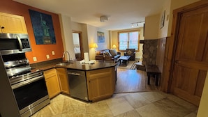 A modern kitchen with a central island, stainless steel appliances, and wooden cabinetry. - River Run - Steps to Ski, Hot Tubs, Heated Pool, Ice Rink (Keystone)