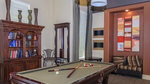 A pool table with balls, a bookshelf with books, and a sofa in a room with patterned carpet. - Vacation worthy Gilbert resort setting (Mesa)