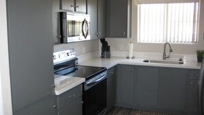 A kitchen with grey cabinets, a microwave, stove, and sink. - Vacation worthy Gilbert resort setting (Mesa)