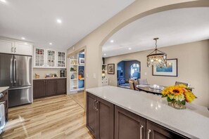 Una cocina moderna con una isla grande, armarios empotrados y un refrigerador de acero inoxidable.