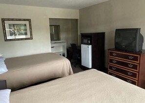 A hotel room with two beds, a desk, a television, and a dresser. - Cozy Inn (Shreveport)