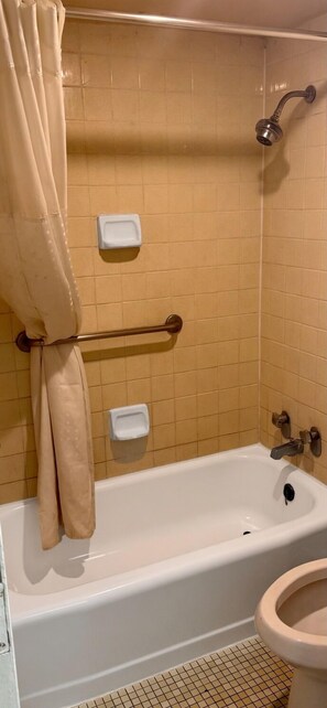 A bathroom with a bathtub, toilet, and shower. - Cozy Inn (Shreveport)