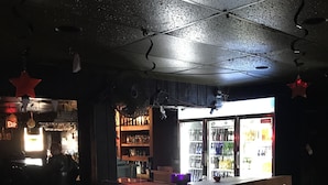 A bar area with a counter, stools, and a refrigerator stocked with beverages.