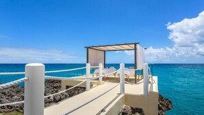 A beachside structure with a covered seating area, ropes, and a view of the ocean. - Sunset Beach View - Luxury Studio next to The Morgan Resort (Maho, Sint Maarten)