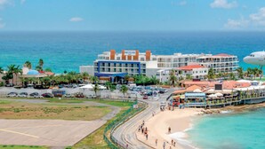 A coastal area with a beach, a road, and a large American Airlines plane. - Sunset Beach View - Luxury Studio next to The Morgan Resort (Maho, Sint Maarten)