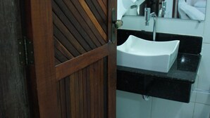 Ein Badezimmer mit Holztür, Waschbecken und einem Spiegel darüber.
