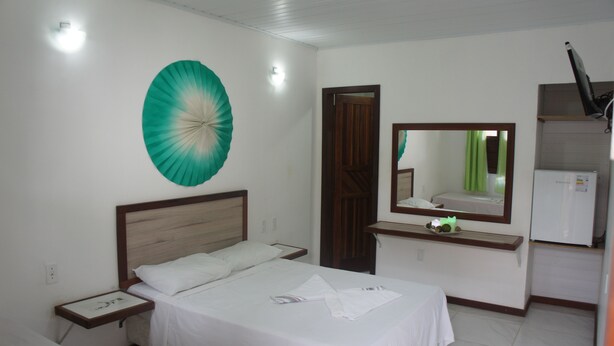 Ein Hotelzimmer mit Bett, Nachttisch, Spiegel und kleinem Schreibtisch mit Lampe.