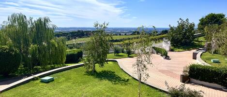 A landscaped garden with a curved pathway, a small pond, and a view of distant fields.