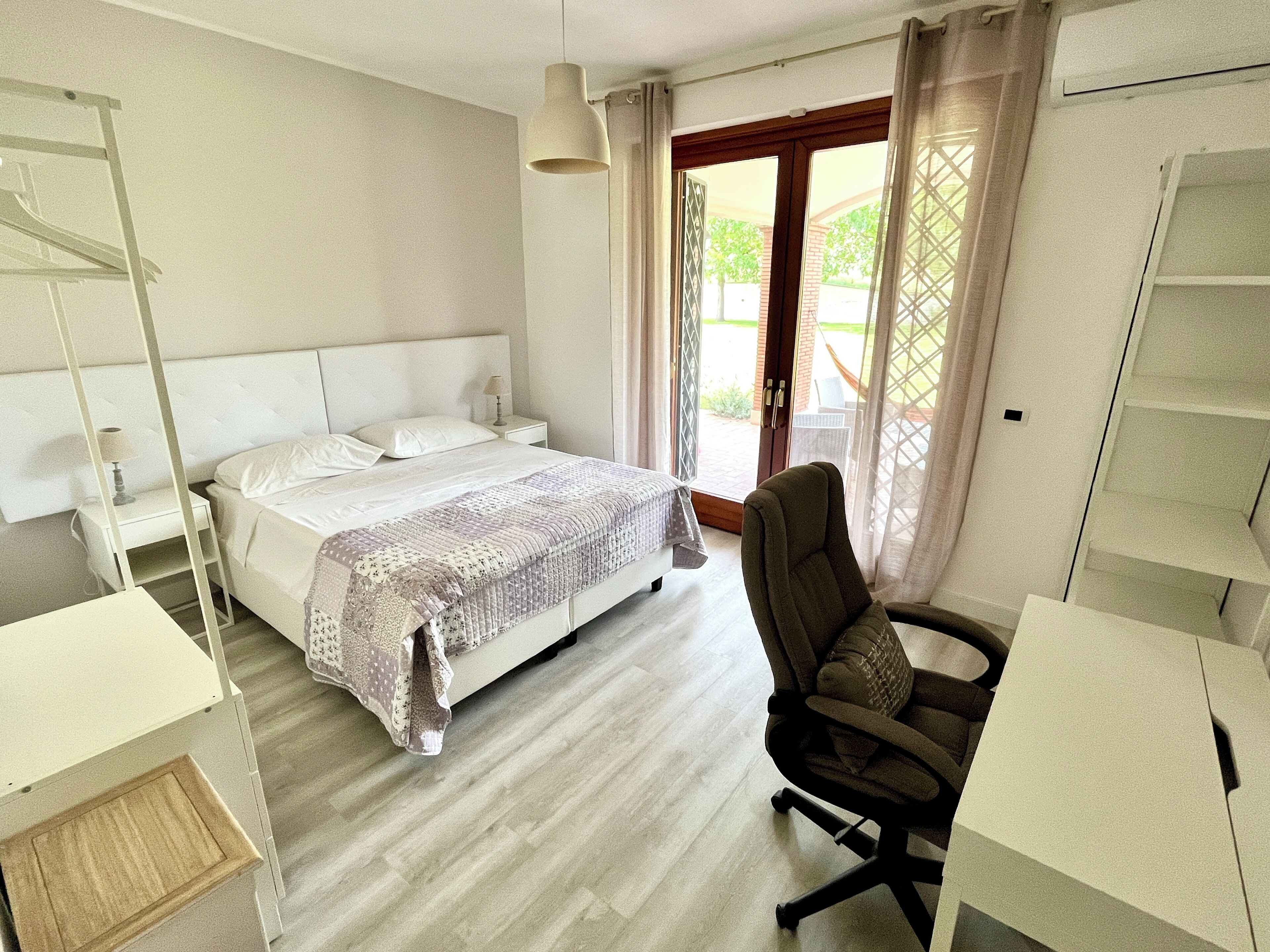 A hotel room with a bed, a desk, a chair, and a window with curtains.