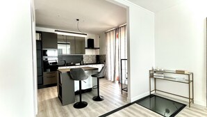 A modern kitchen with a central island, bar stools, and a glass-top table. - Cape House (Albano Laziale)