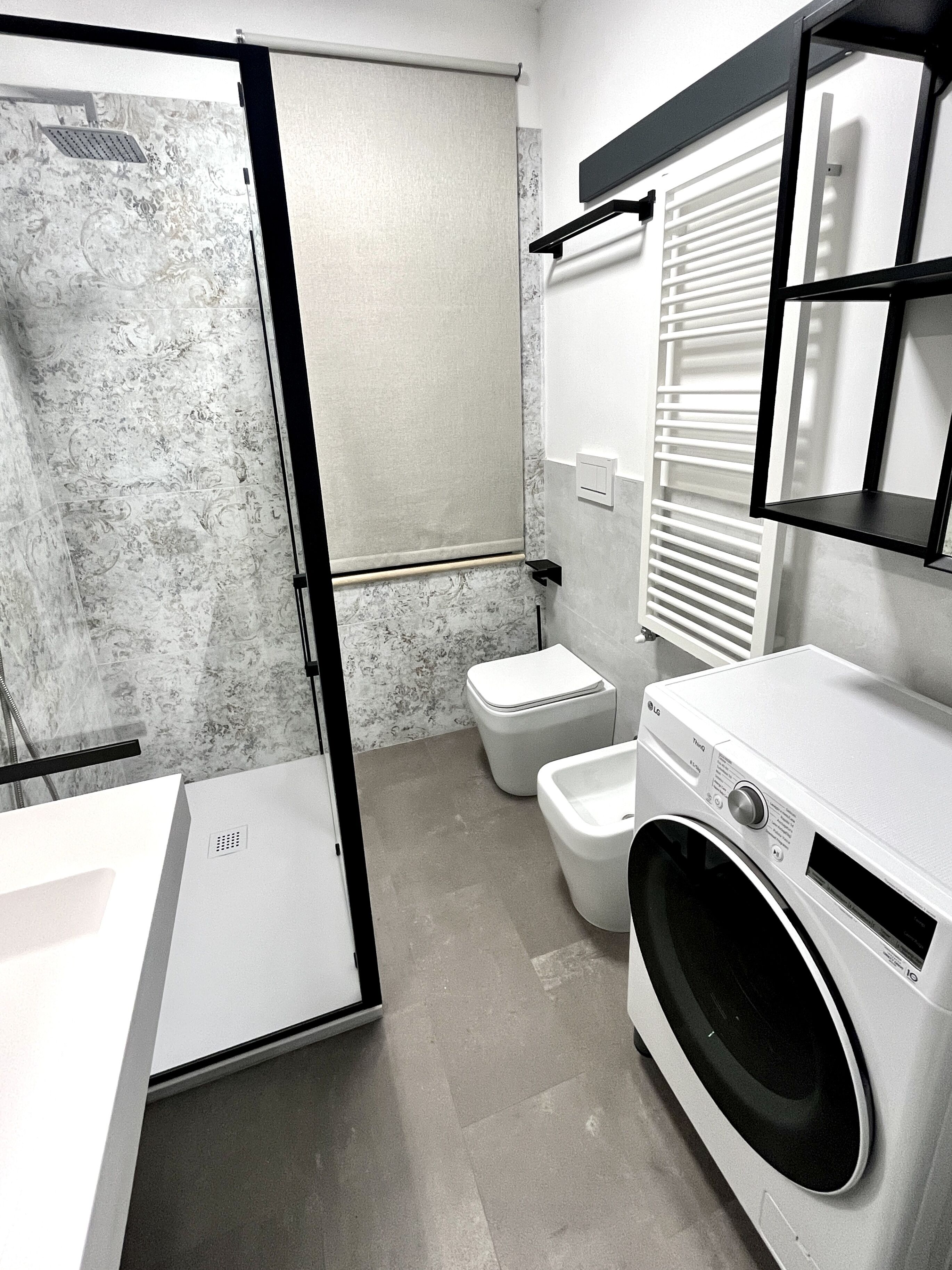 A modern bathroom with a shower, toilet, and washing machine.
