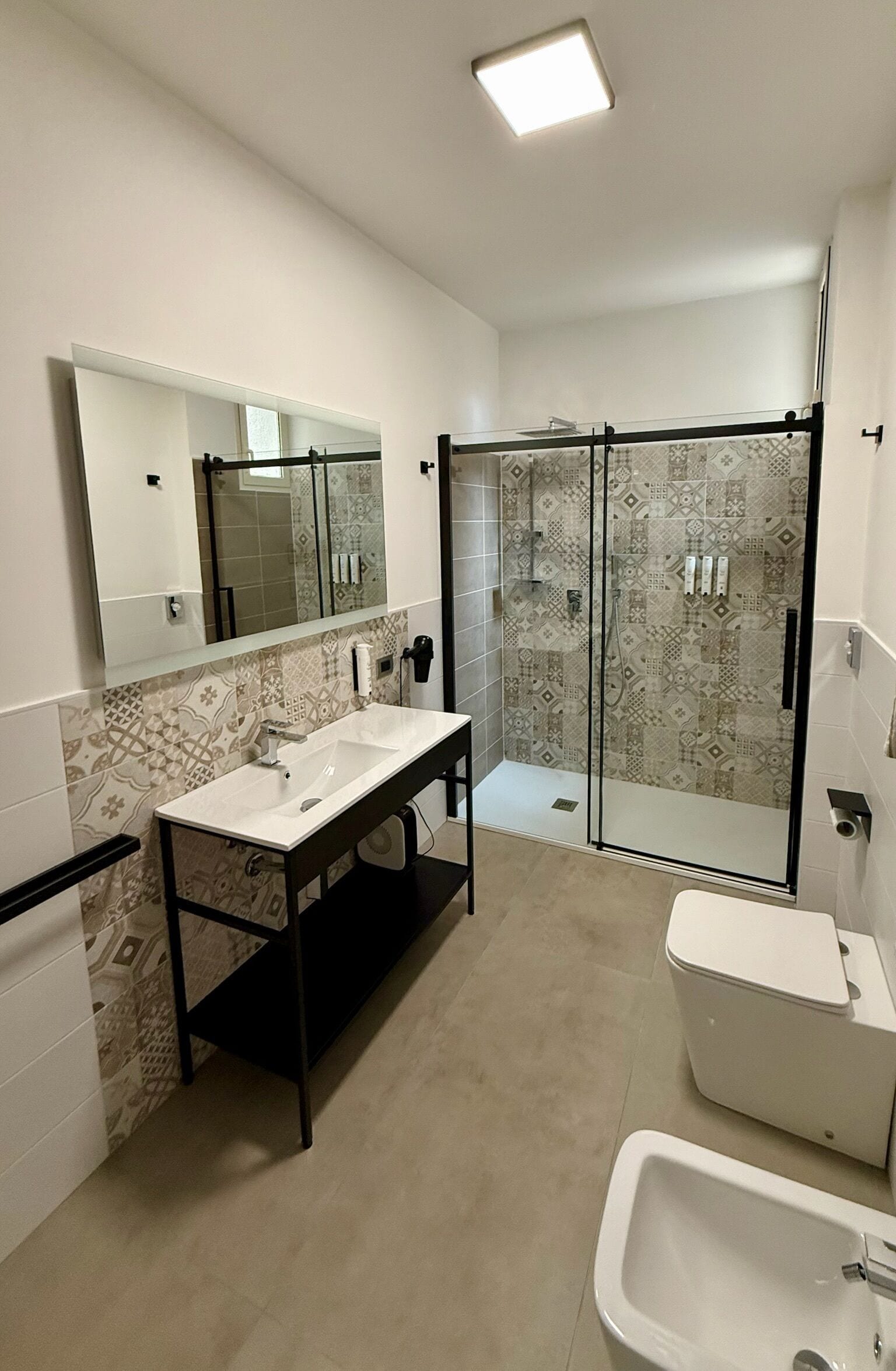 Un baño moderno con un espejo grande, lavamanos doble, cabina de ducha e inodoro.
