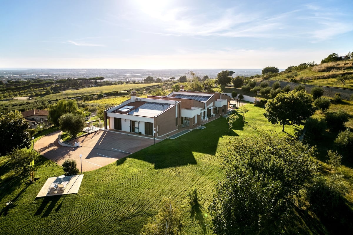 A modern house with a flat roof, large windows, and a spacious lawn.