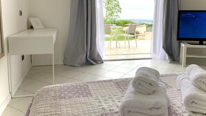 A hotel room with a bed, a desk, a TV, and a view of the outdoors. - Cape House (Albano Laziale)